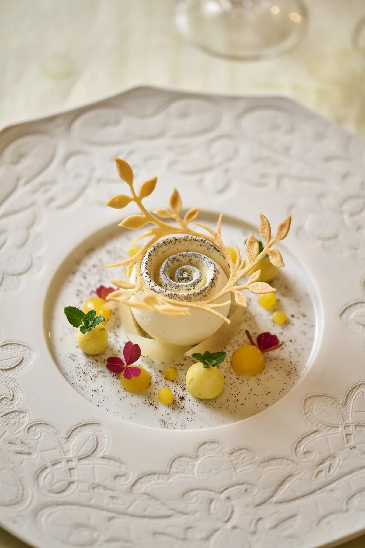 Postre en forma de rosa acompañado de pequeños adornos dorados en Villa Marie