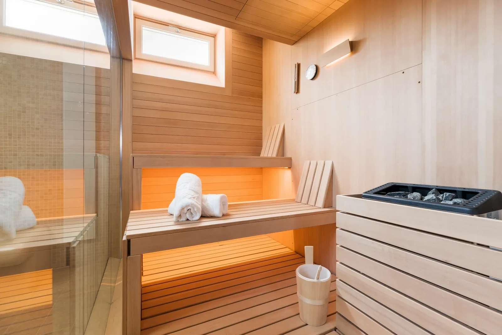 Banquettes et poêle du sauna derrière une paroi vitrée à Villa Marie