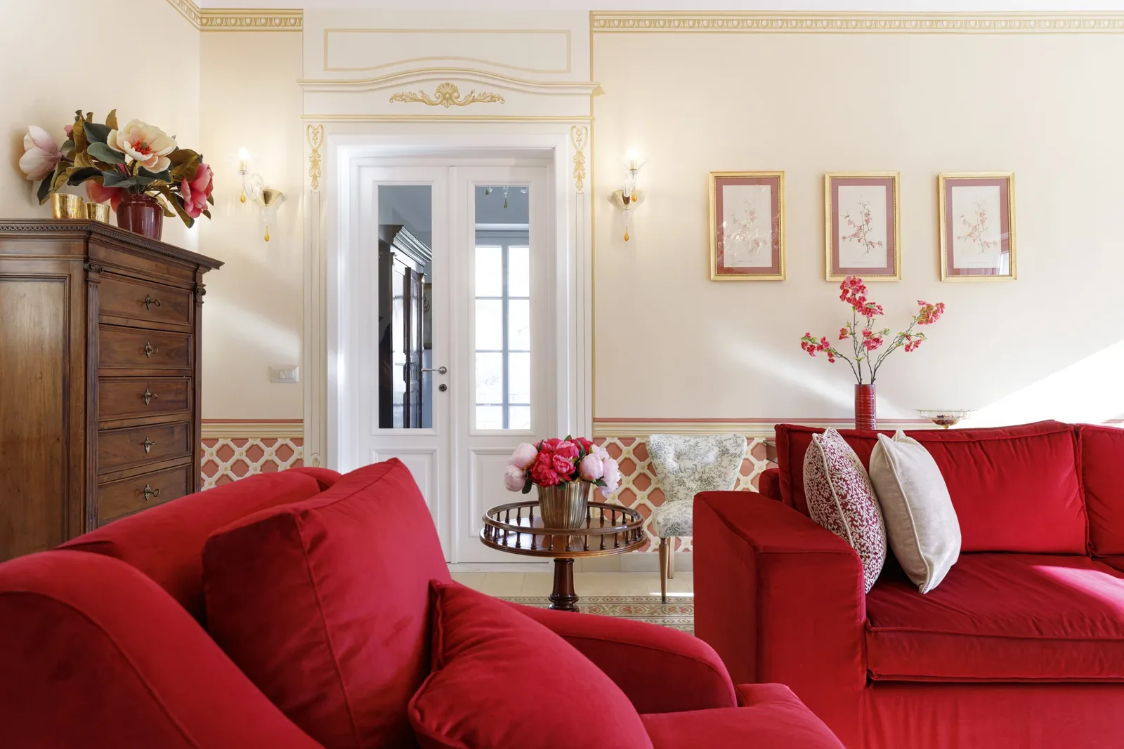 Canapés rouges, bouquet de fleurs et commode dans le salon de Villa Marie