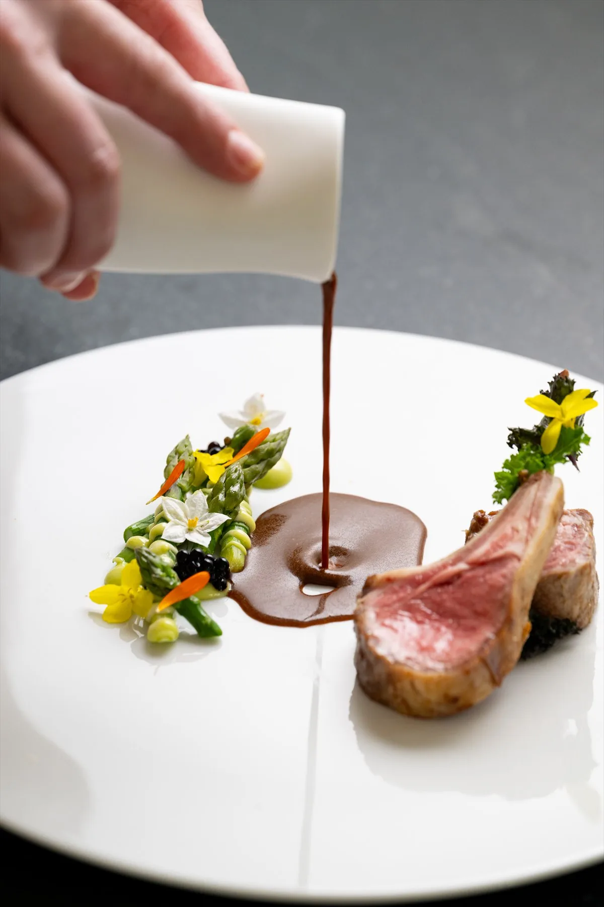 Le chef privé verse une sauce sur un plat d’agneau à Villa Marie