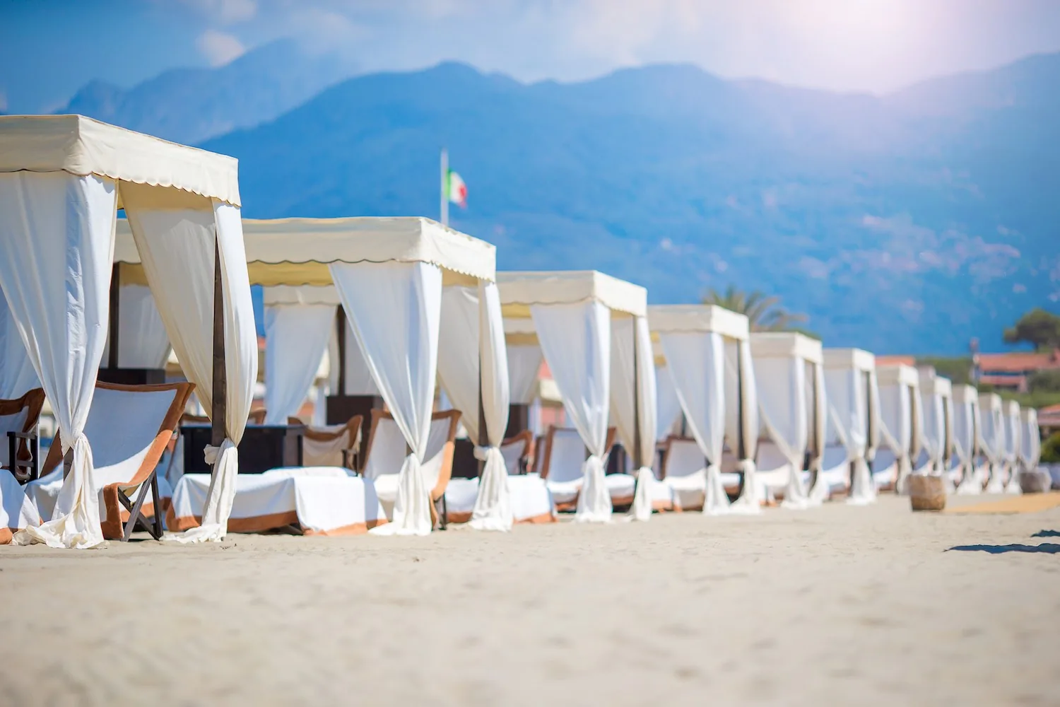 Élégantes pergolas de plage à Forte dei Marmi, avec les Alpes apuanes à l’horizon