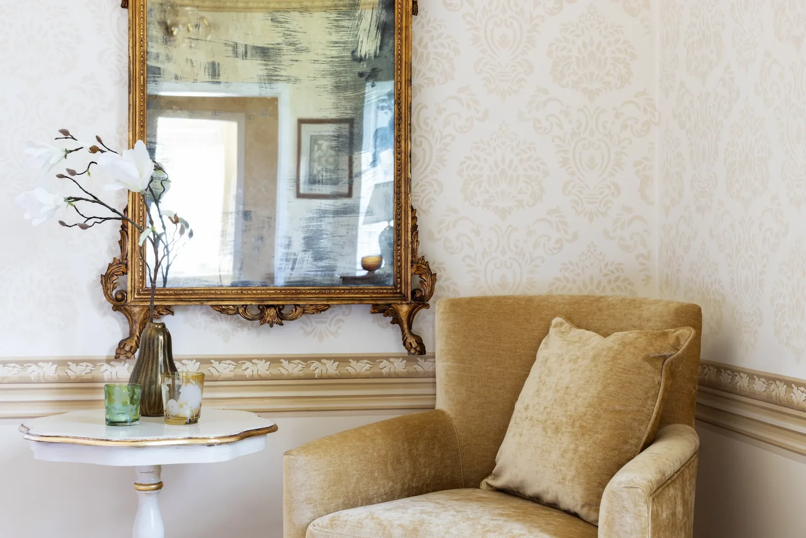 Fauteuil jaune et table sous un miroir doré à Villa Marie