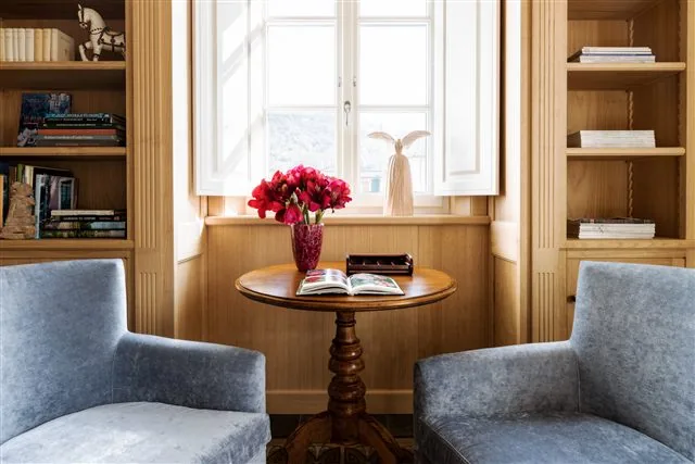 Fauteuils bleus et table fleurie dans la bibliothèque de Villa Marie