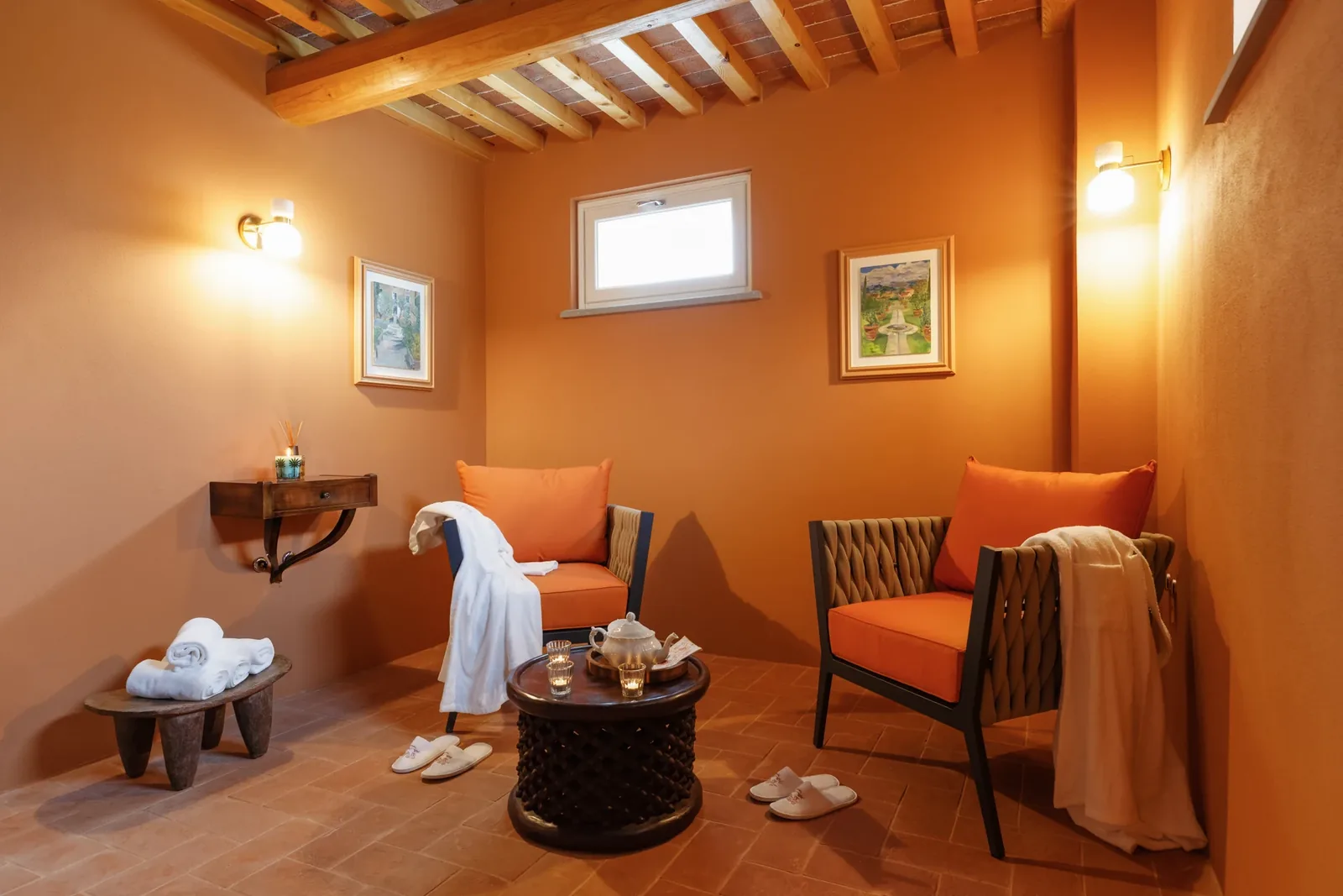 Fauteuils orange, peignoirs et plateau de thé dans l’espace détente du spa