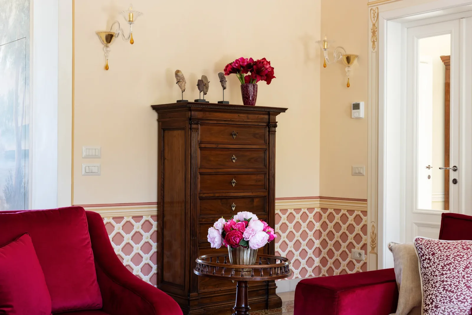 Fauteuils rouges et commode ancienne dans le salon de Villa Marie