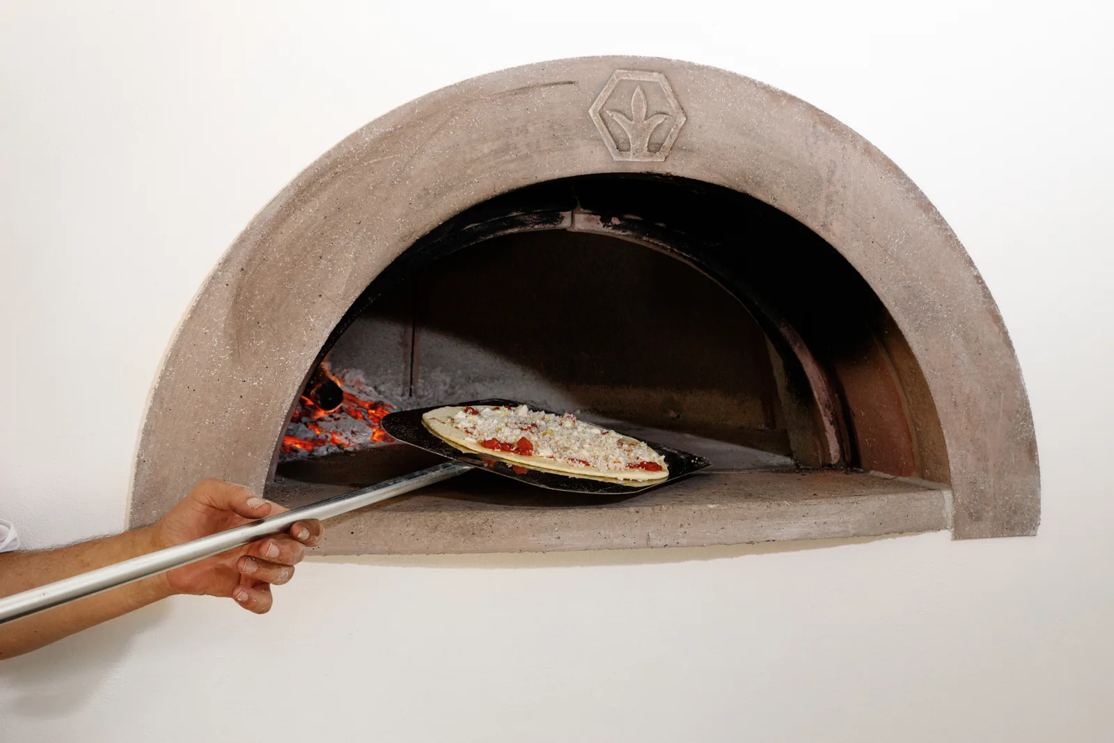 Pizza enfournée à l’aide d’une pelle dans le four de Villa Marie