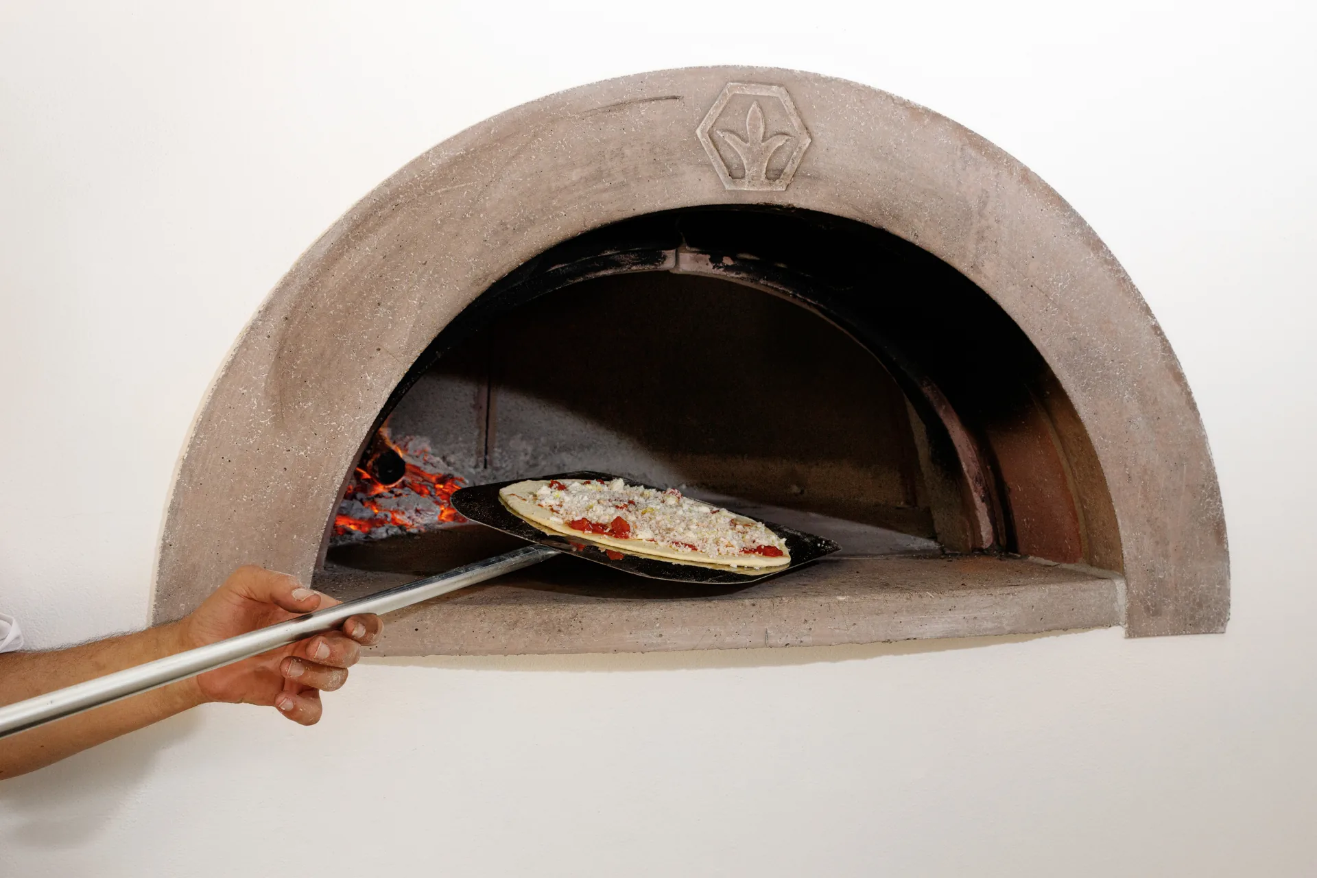Pizza enfournée à l’aide d’une pelle dans le four de Villa Marie