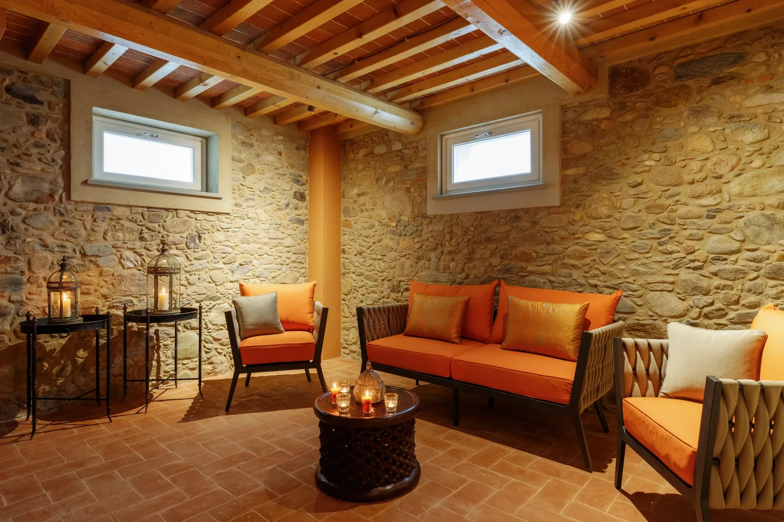 Salon de détente du spa avec canapé orange et mur en pierre à Villa Marie