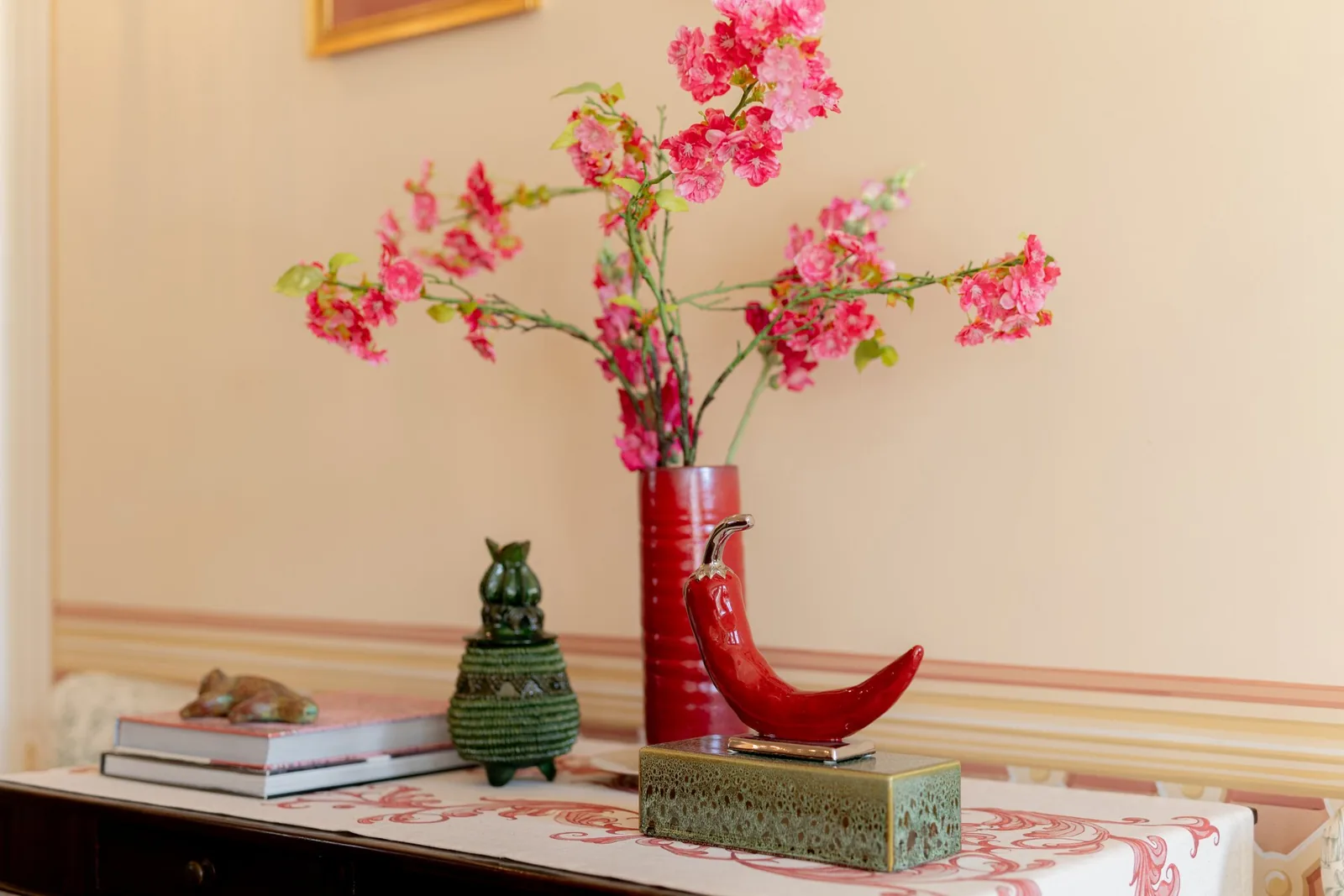 Vase rouge fleuri et objets décoratifs sur une console de Villa Marie