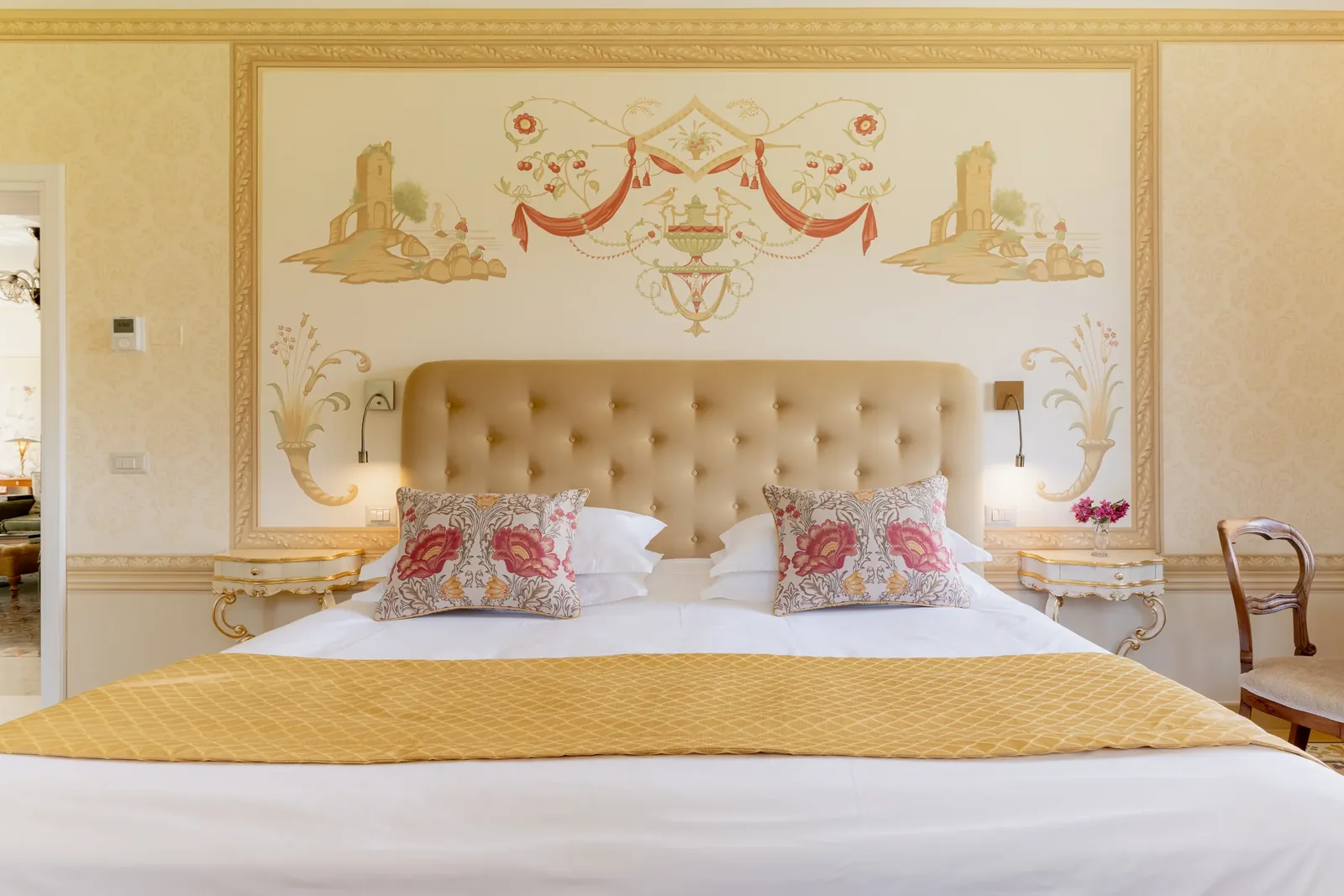 Letto della Camera gialla di Villa Marie con cuscini floreali e copriletto giallo