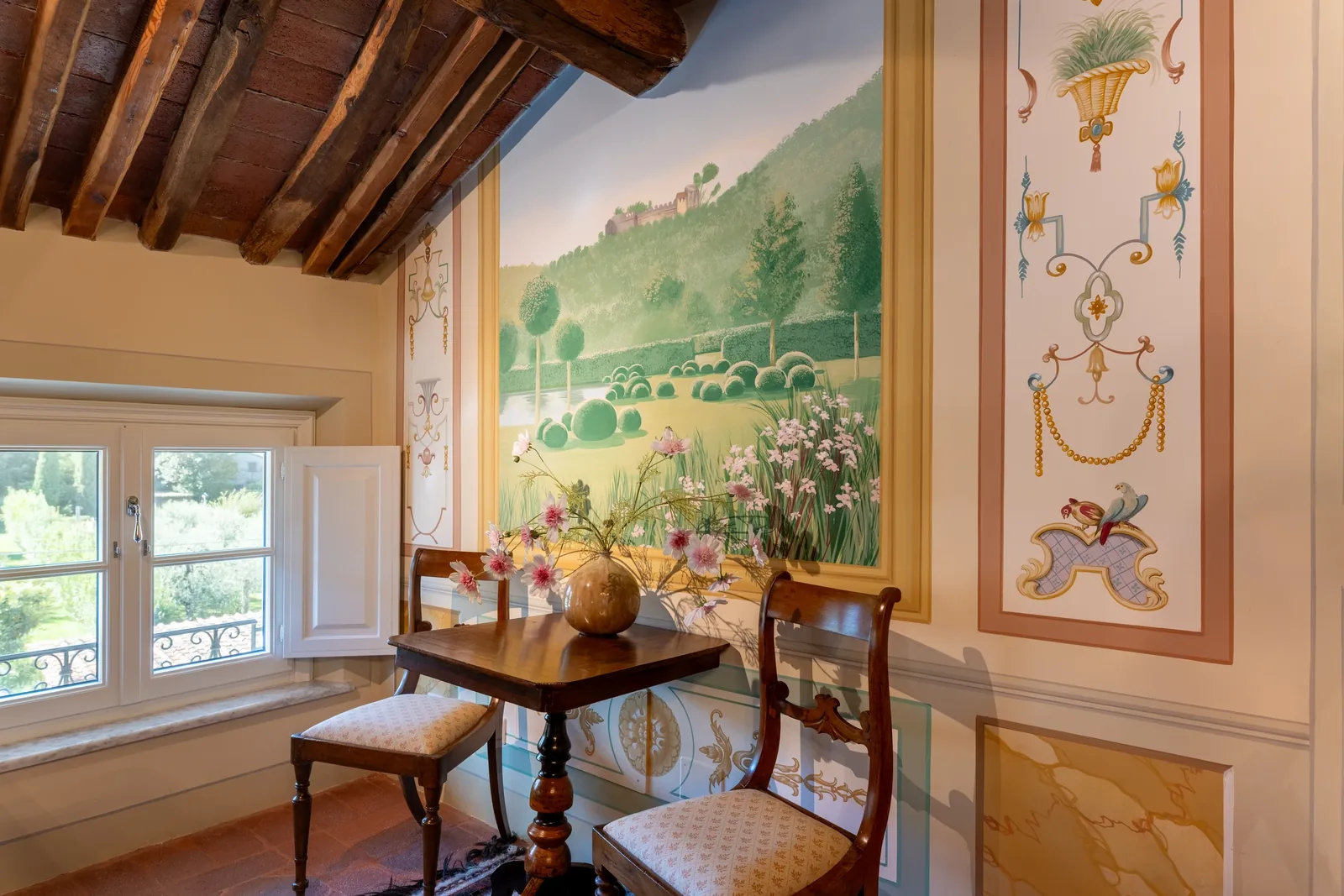 Tavolo vicino alle finestre e murale del soggiorno al secondo piano di Villa Marie